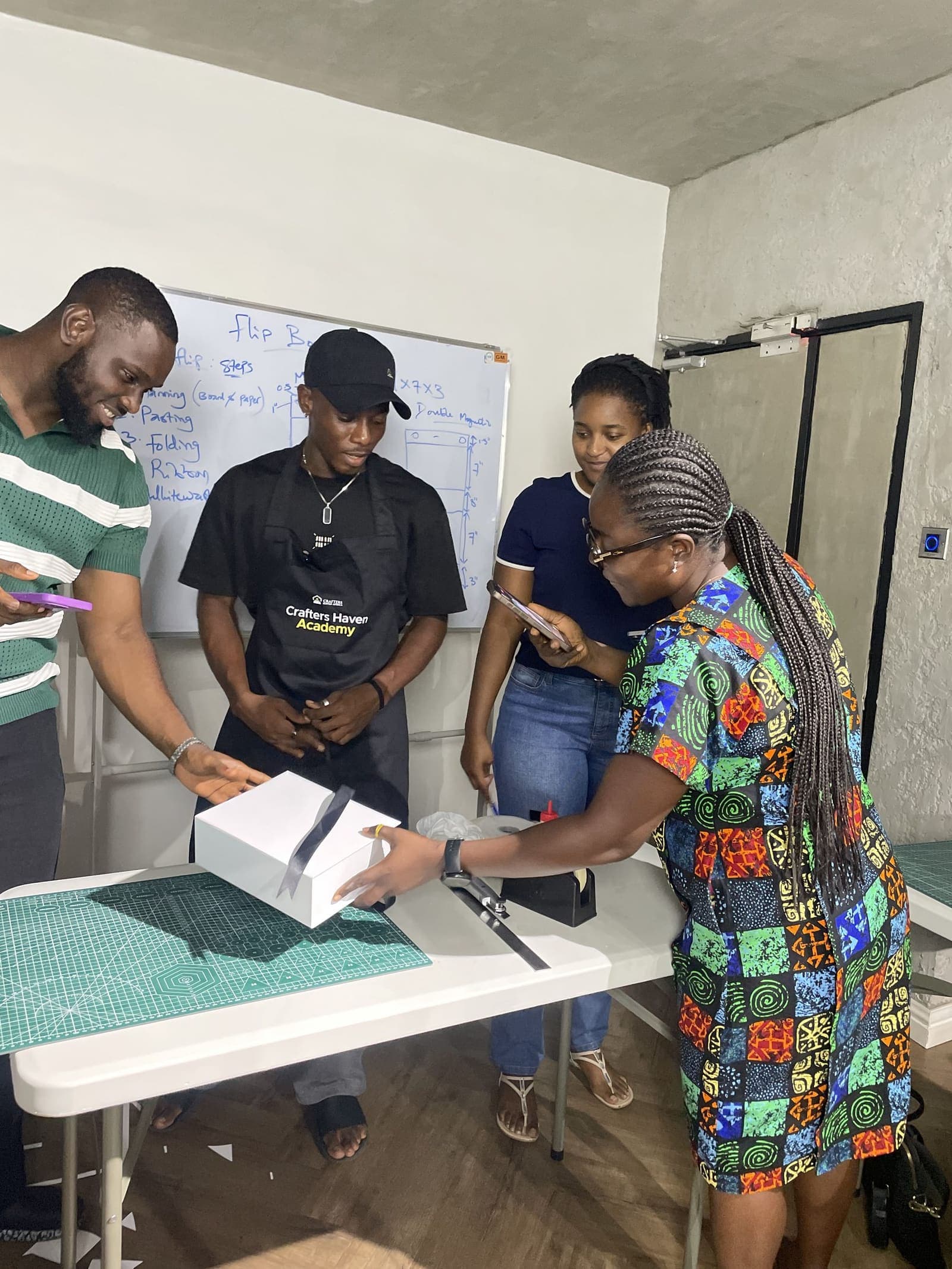 An Academy trainer and members working through a box build, the steps written up on the whiteboard behind them
