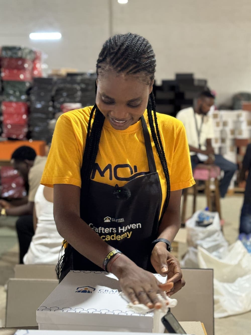 A member in a Crafters Haven Academy apron finishing a branded box