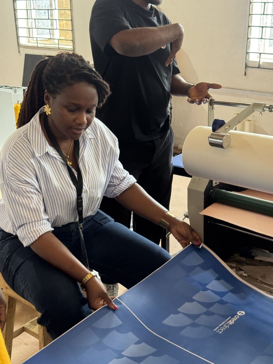 A member feeding a printed sheet through a roll laminator on the production floor